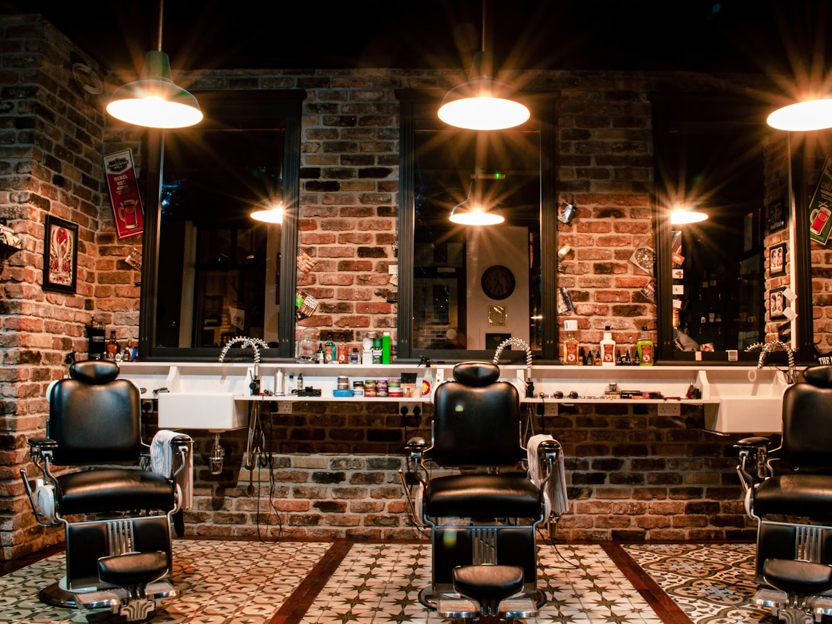 Barber chairs under warm lights in a brick-walled shop