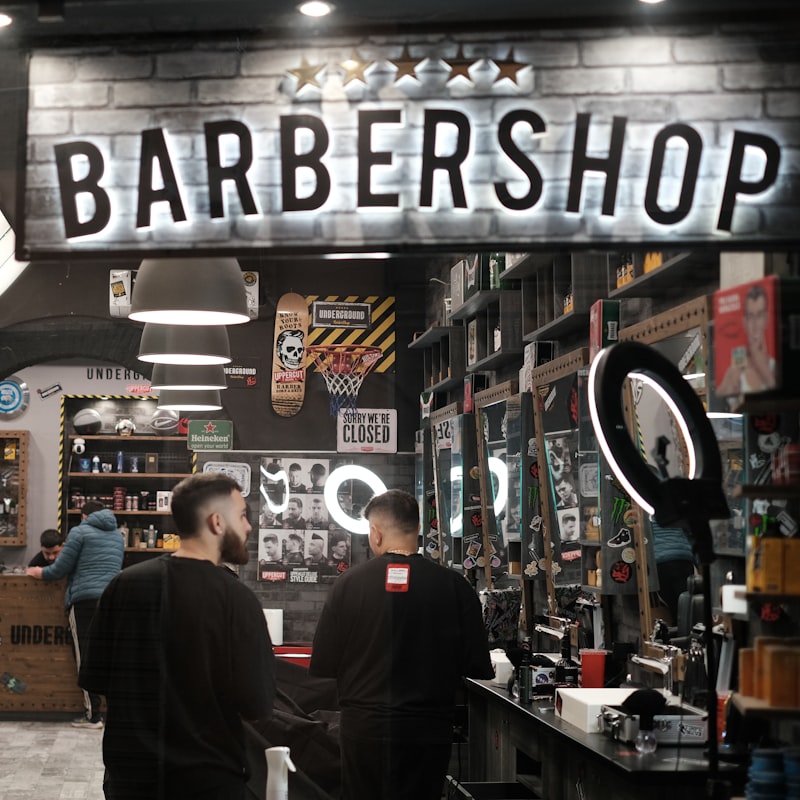 Barbers at work under the shop sign